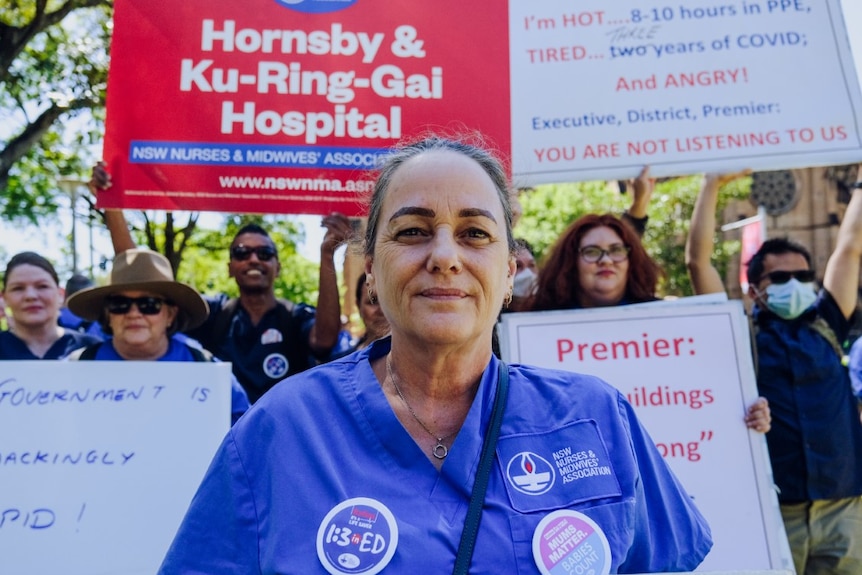 A woman looking at the camera with signs behind her