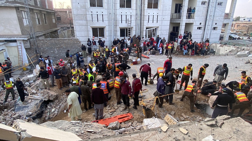 Security officials and rescue workers search bodies at the site of suicide bombing.