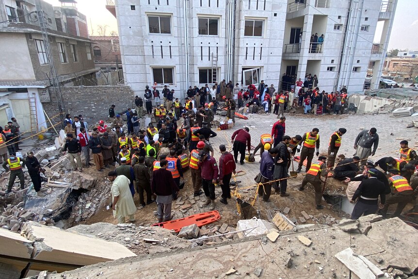 Security officials and rescue workers search bodies at the site of suicide bombing.