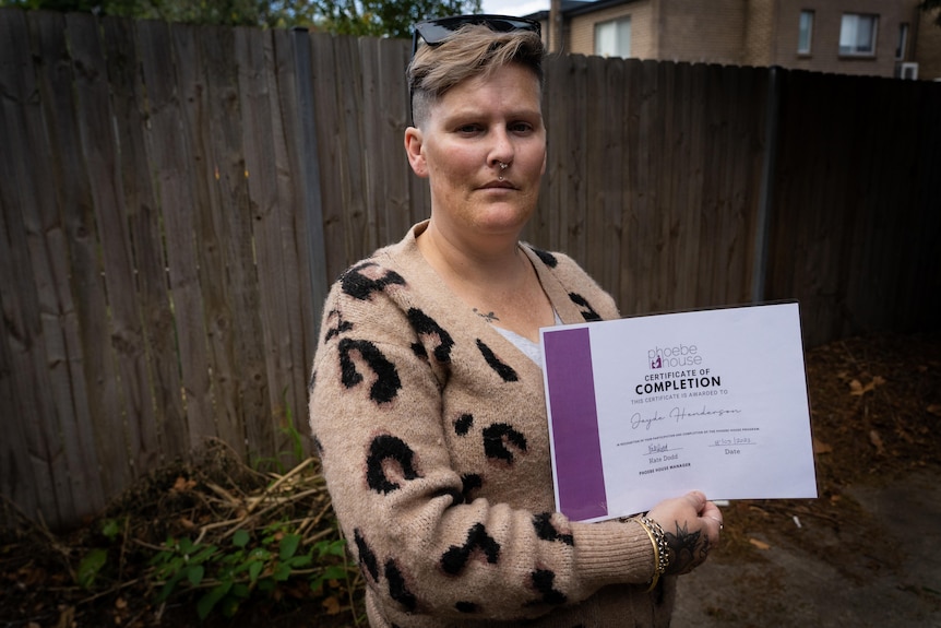 A woman holds her graduation certificate.