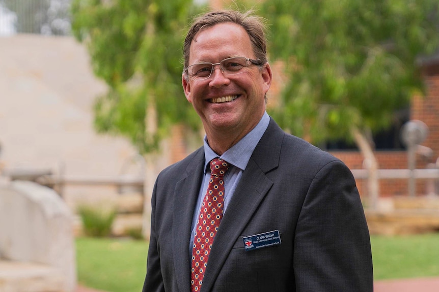 A mid-shot of a smiling Guilford Grammar Preparatory School head Clark Wight in a suit and tie outdoors.