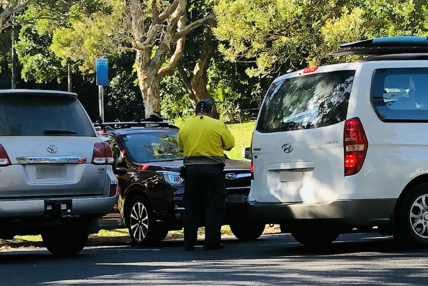 A council ranger writes out fines for people caught sleeping in their cars and vans.