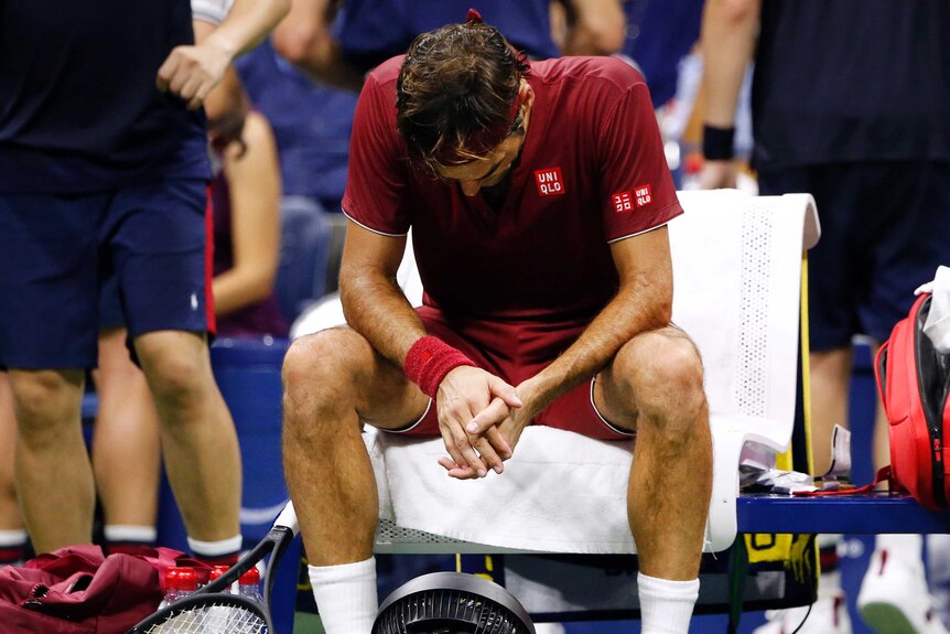 Roger Federer looks downcast as he sits in front of a small fan during a changeover