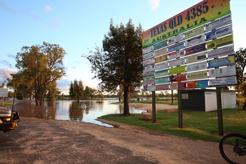 A Texas sign with flooding in the background.