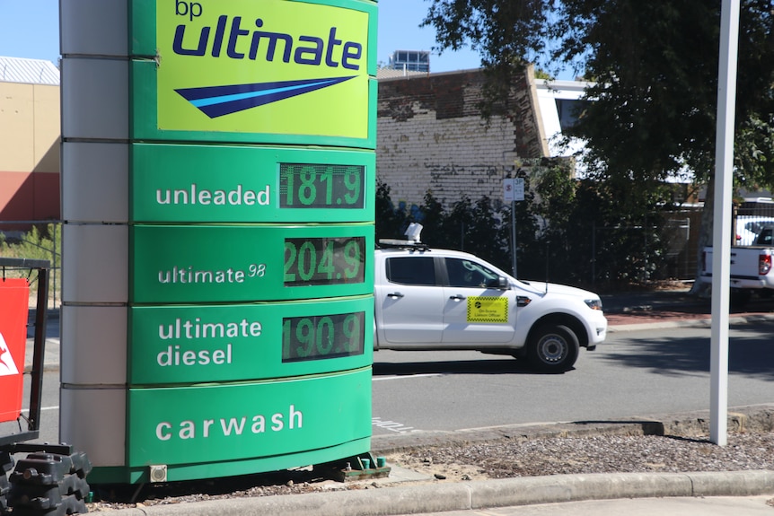 A green sign advertising petrol prices.
