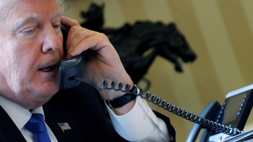 US President Donald Trump speaks on the phone in the Oval Office at the White House in Washington.