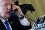 US President Donald Trump speaks on the phone in the Oval Office at the White House in Washington.