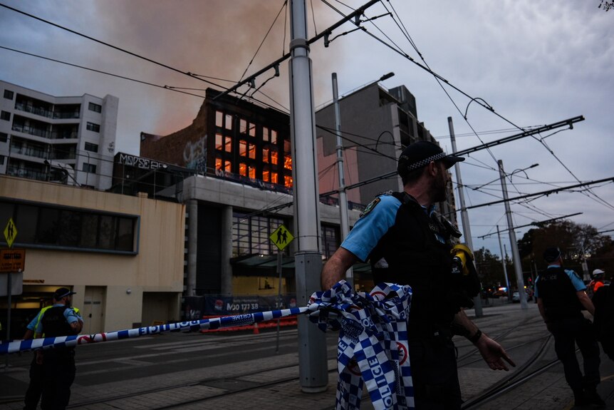 a police man cordons off an area where a fire broke out in sydney cbd