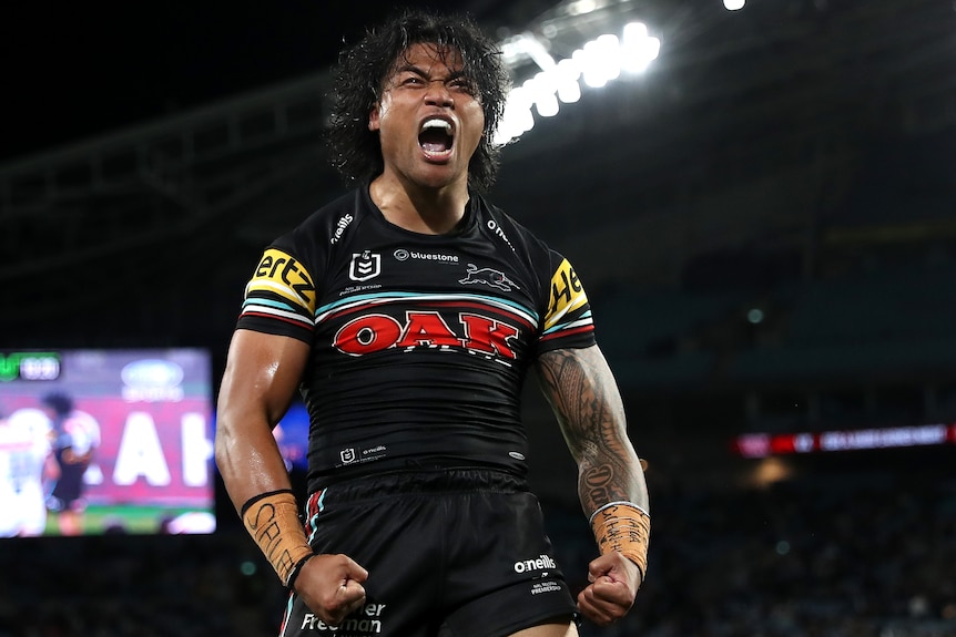 An NRL player stand allow, yelling wiht excitement, puffing his chest.