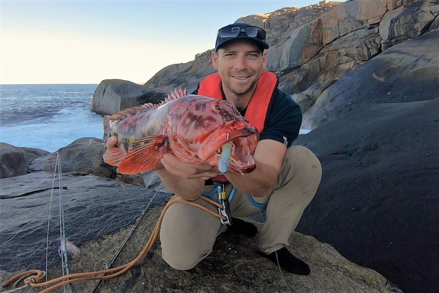 Gideon Mettam poses with a bright red harlequin which he caught from the rocks.
