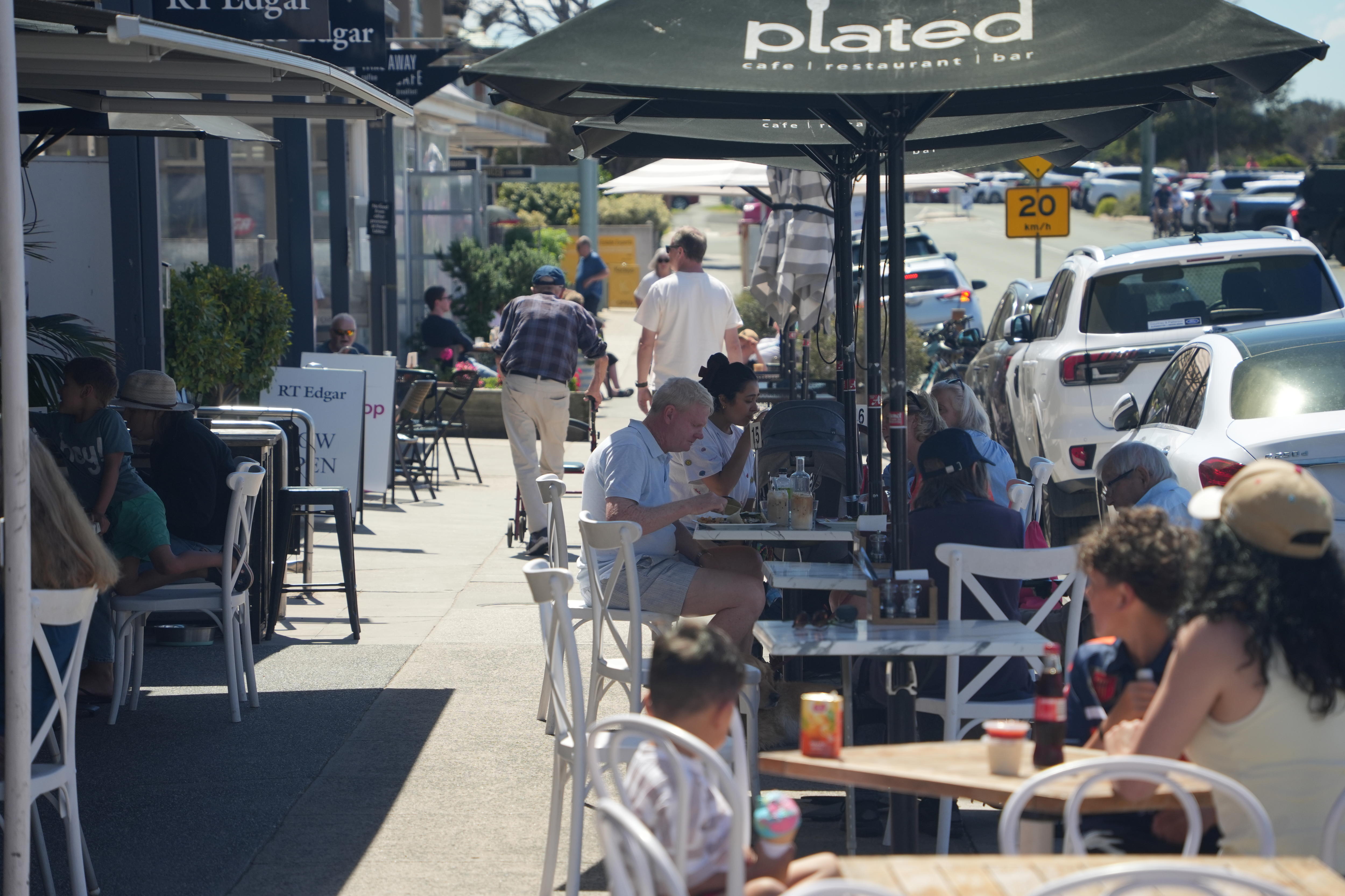 A shot of patrons sitting at cafes in the main street of Point Lonsdale. 