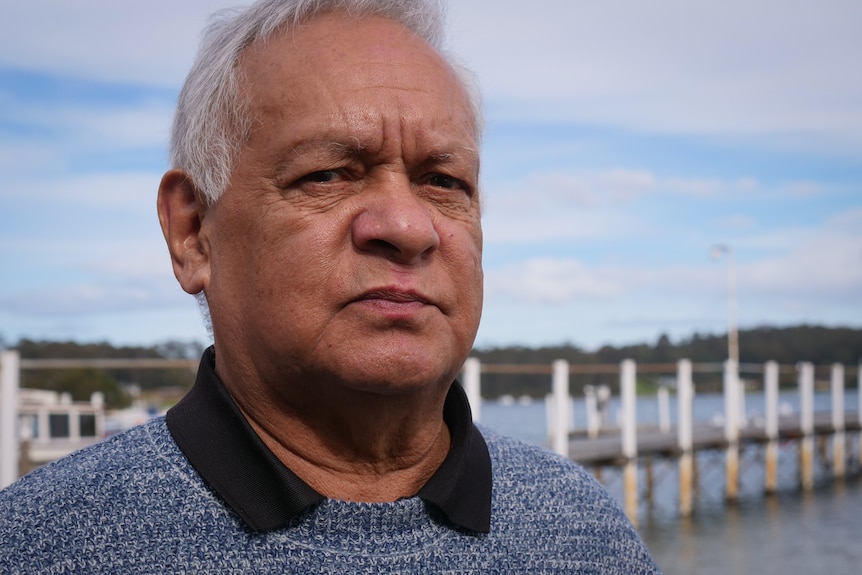 Close up of man near lake with wooden jetty behind him