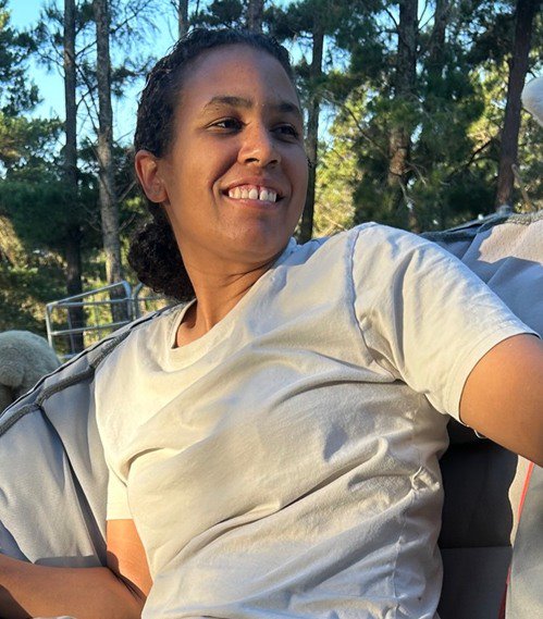 A woman with dark features smiles looking away from the camera