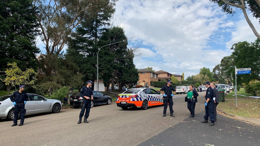 A group of police officers and detectives stand in front of a cordoned off crime scene at Cherrybrook, in Sydney's north.