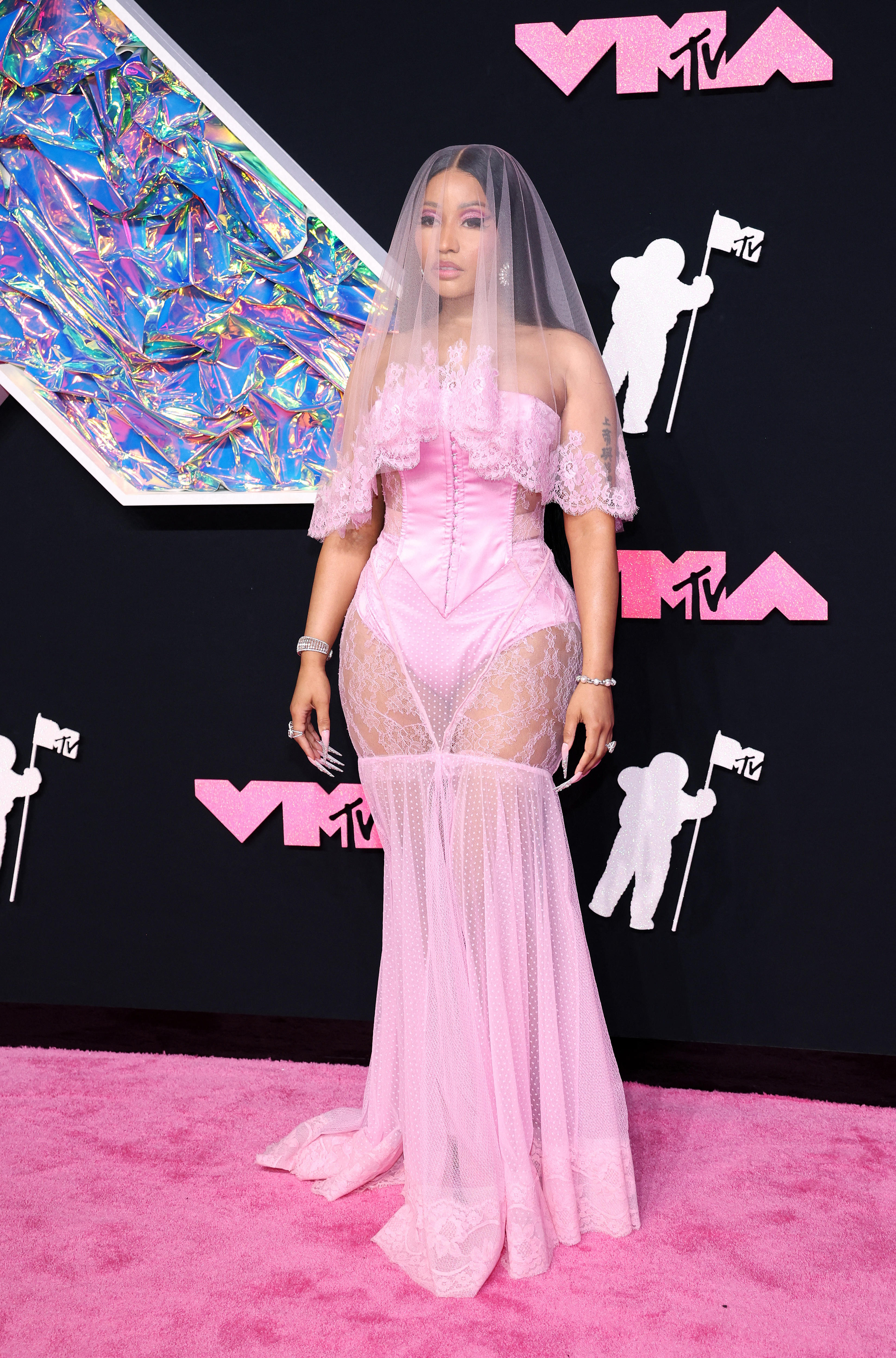 Nicki Minaj is wearing a pink veil with a pink laced dress