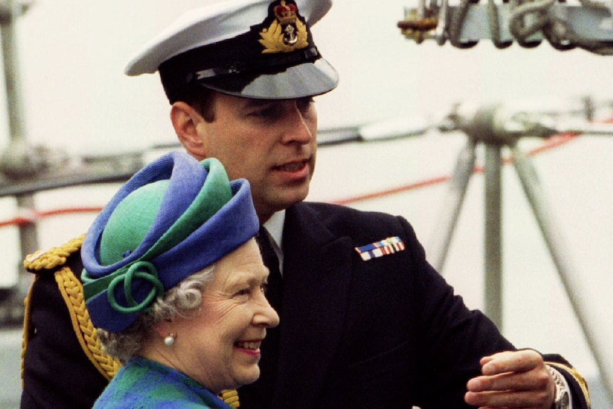 The Queen and Prince Andrew stand aboard a Royal Navy ship deck as the Royal directs the sovereign to another location.