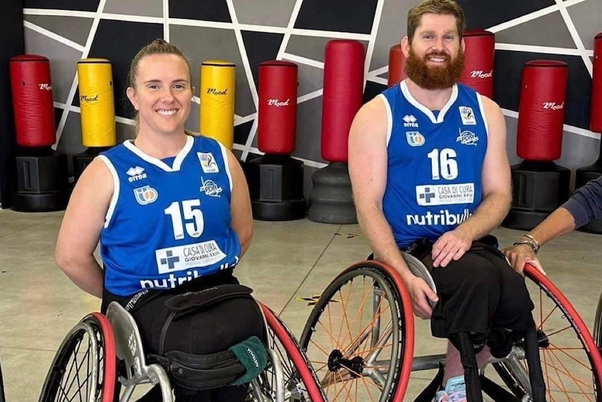 Smiling woman and man in wheelchairs on sporting court