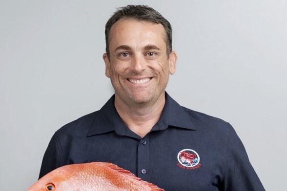 Shawn McAtamney smiles holding tropical fish
