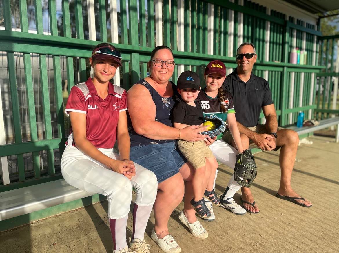A family sitting in a baseball dugout.