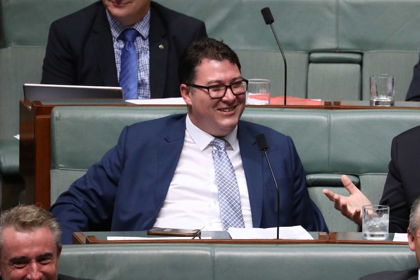 A bespectacled man in a dark suit – MP George Christensen – sits in Parliament.