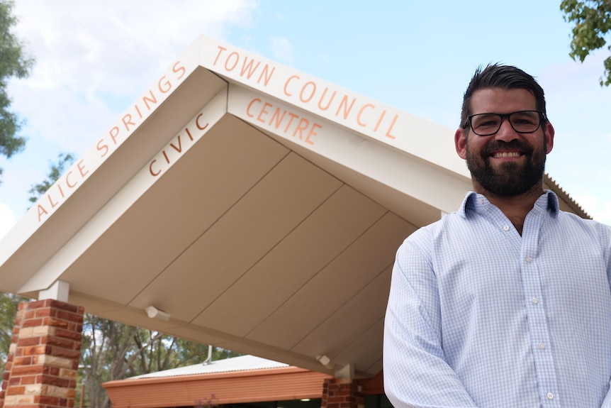 Building with the words 'Alice Springs Town Council Civic Centre' and a man standing to the right of the frame wearing a business shirt