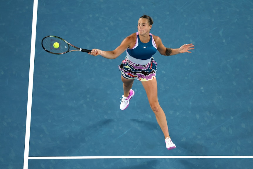 A tennis player is pictured with both feet off the ground as she reaches to hit a power forehand at the Australian Open.