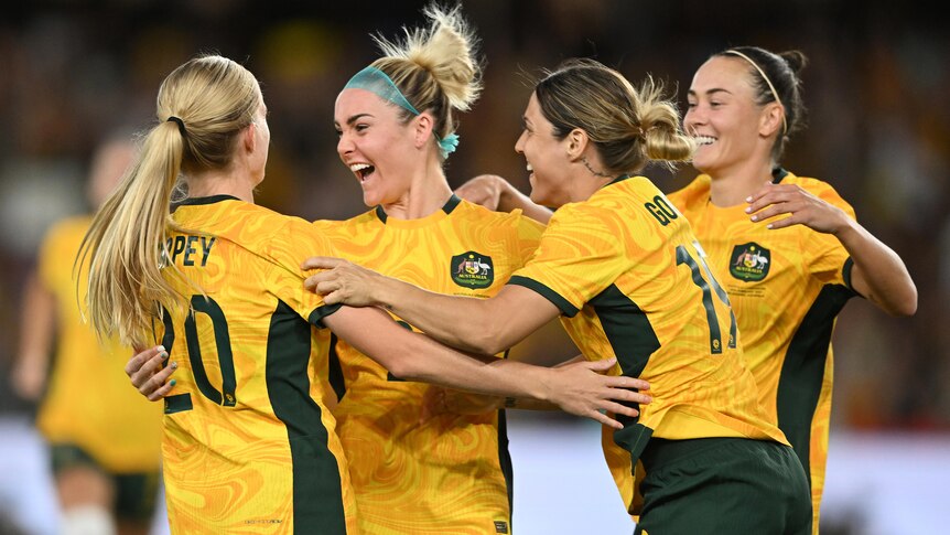 Four Matildas players come together to celebrate a goal.
