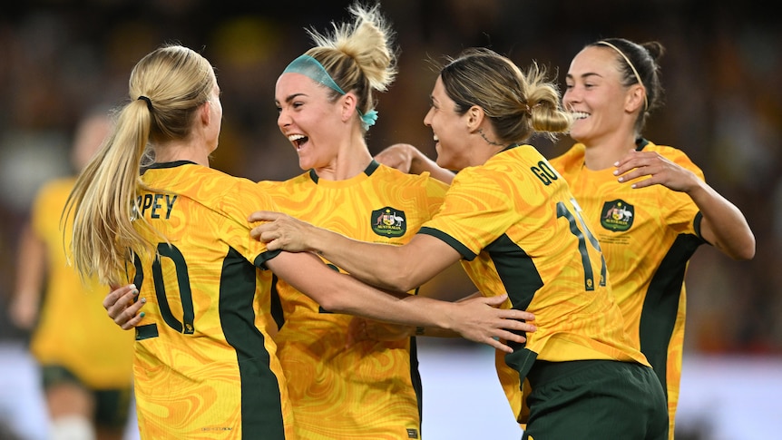 Four Matildas players come together to celebrate a goal.