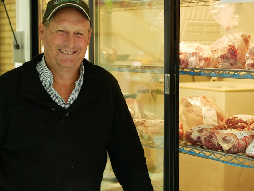 A man smiling standing in front of a cool room fridge of lamb