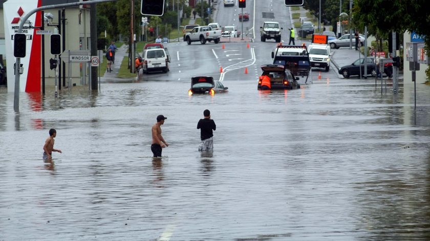 Water world: Residents in the Brisbane suburb of Wilston wade through floodwaters.