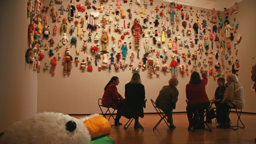 People in front of wall of soft toys