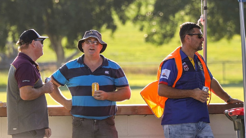 Men at sporting match hold beers while in conversation