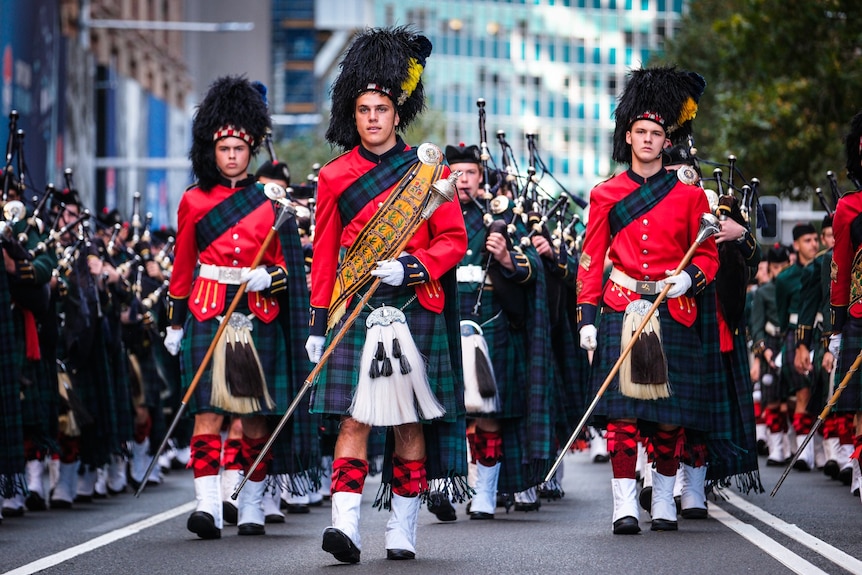 Men in kilts and red tunics march in an Anzac Day parade