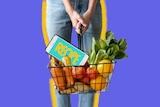 A woman holds a basket containing groceries and a smartphone designed to show ways to save time shopping