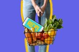 A woman holds a basket containing groceries and a smartphone designed to show ways to save time shopping