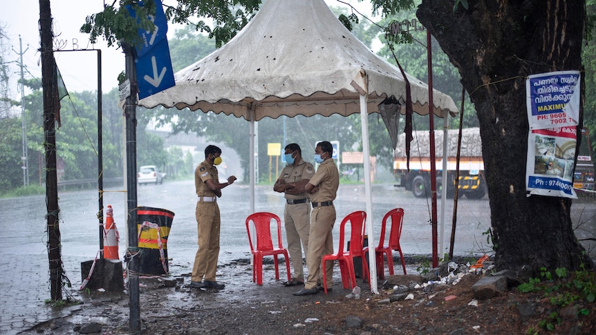 Police stand underneath a tent as rain falls