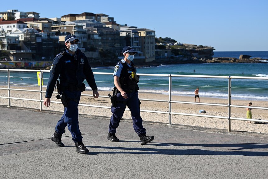 Two police officers walk along the Bondi Beach shore line.