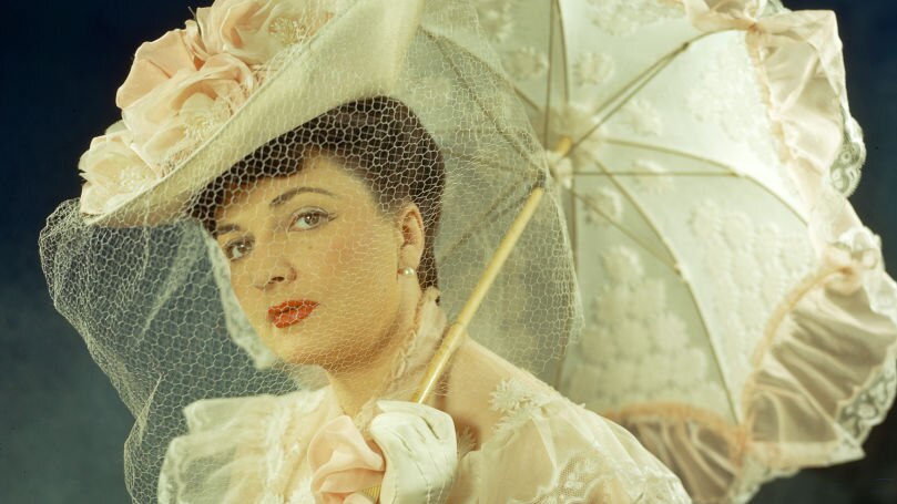 Portrait of a woman dressed in Edwardian clothes with an umbrella. 