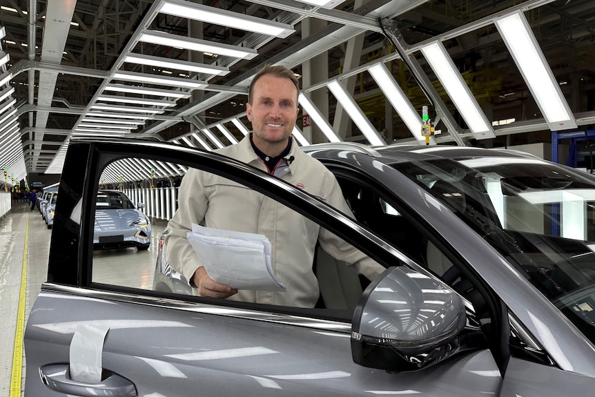 A man stands in a car factory.