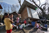 Residents stand amid damaged homes following Typhoon Rai