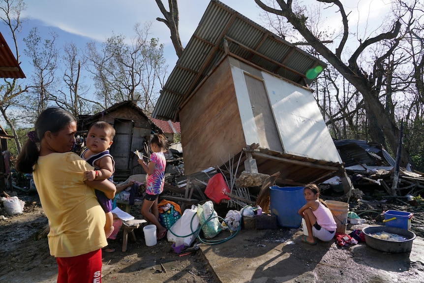 Residents stand amid damaged homes following Typhoon Rai