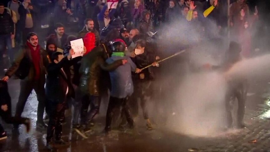 Protesters form a human shield around woman waving EU flag in Georgia