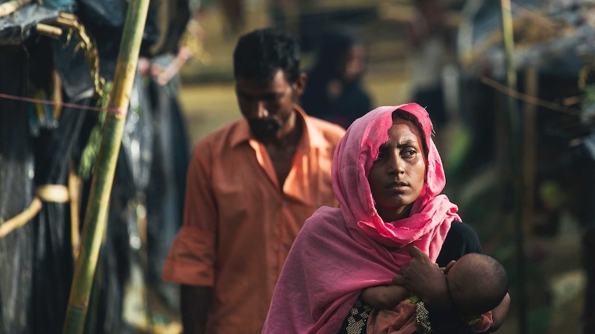 A woman carries her child through a camp in Cox's Bazaar, Bangladesh.