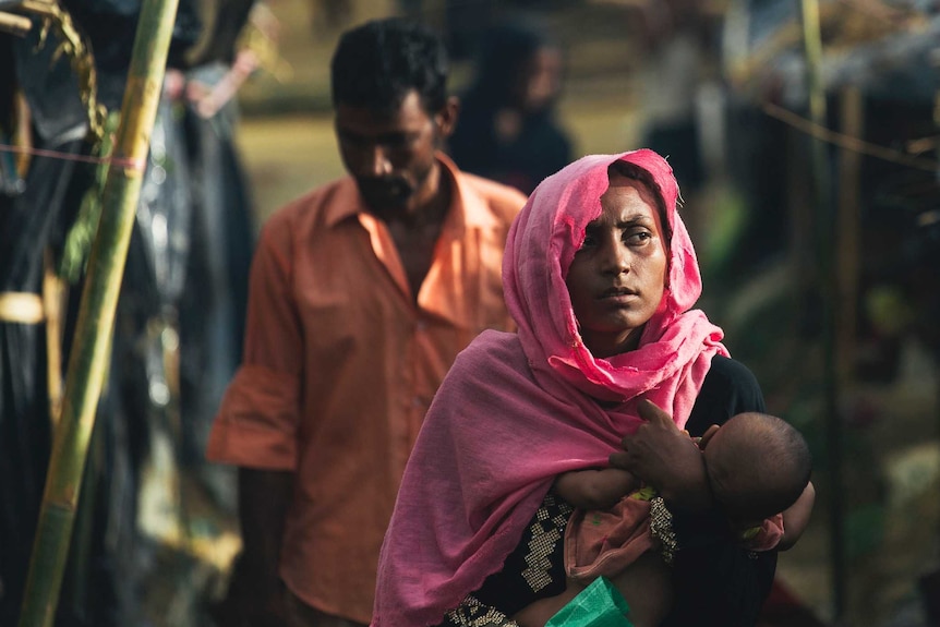 A woman carries her child through a camp in Cox's Bazaar, Bangladesh.