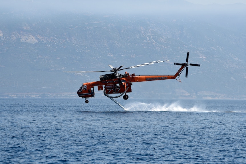 A helicopter fills up with water from the sea near Lampiri village, east of Patras city, Greece.