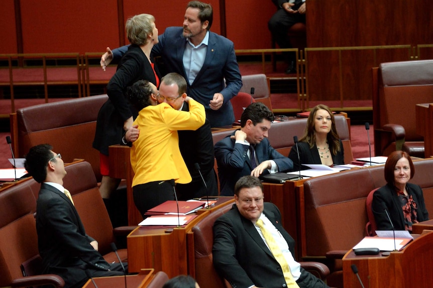 Jacqui Lambie and Ricky Muir (centre) hug during the swearing in of new senators.