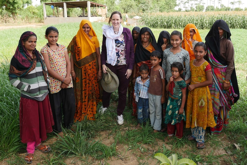 A group of women standing in a field of cereal crops smiling for the camera