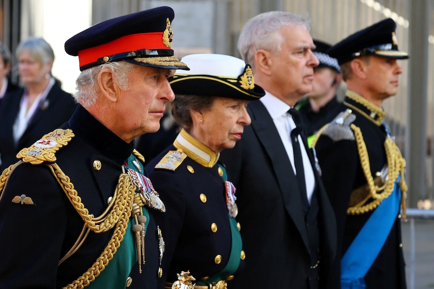 King Charles III, Princess Anne and Prince Edward in military dress and Prince Andrew in a suit walk abreast.
