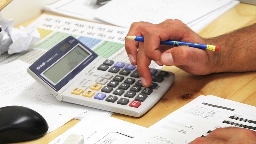 A man's hand using a calculator.