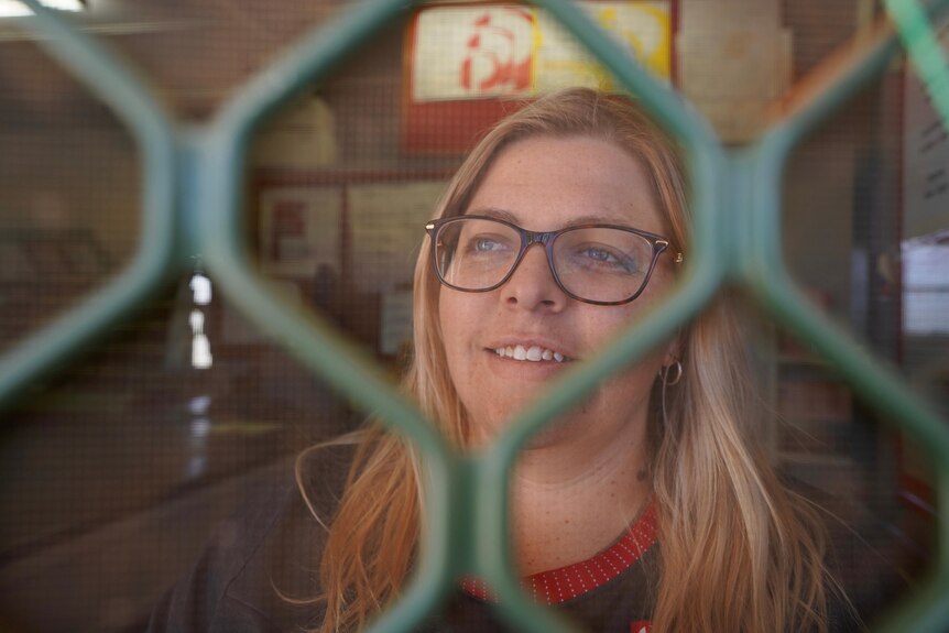 Woman wearing glasses staring through door